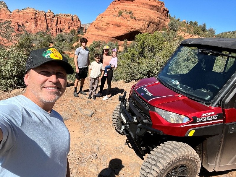 David Newman and his family beside a red off-road vehicle on a red rock trail in northern Arizona