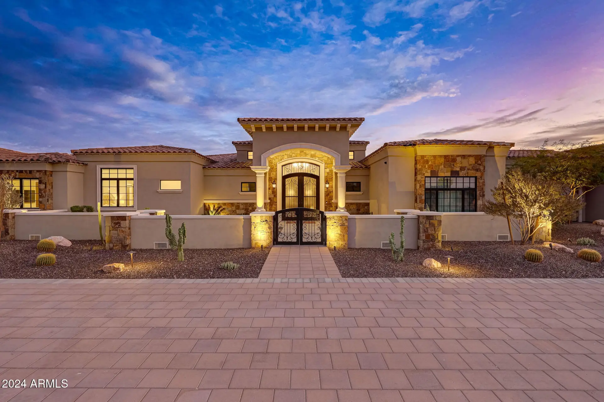 Front elevation of 11935 E Buckskin Trail at dusk with stone accents and an iron courtyard gate