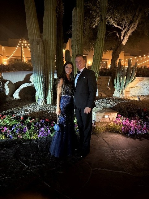 David Newman and his fiancé Kira dressed for an evening event in an Arizona desert garden lit by string lights