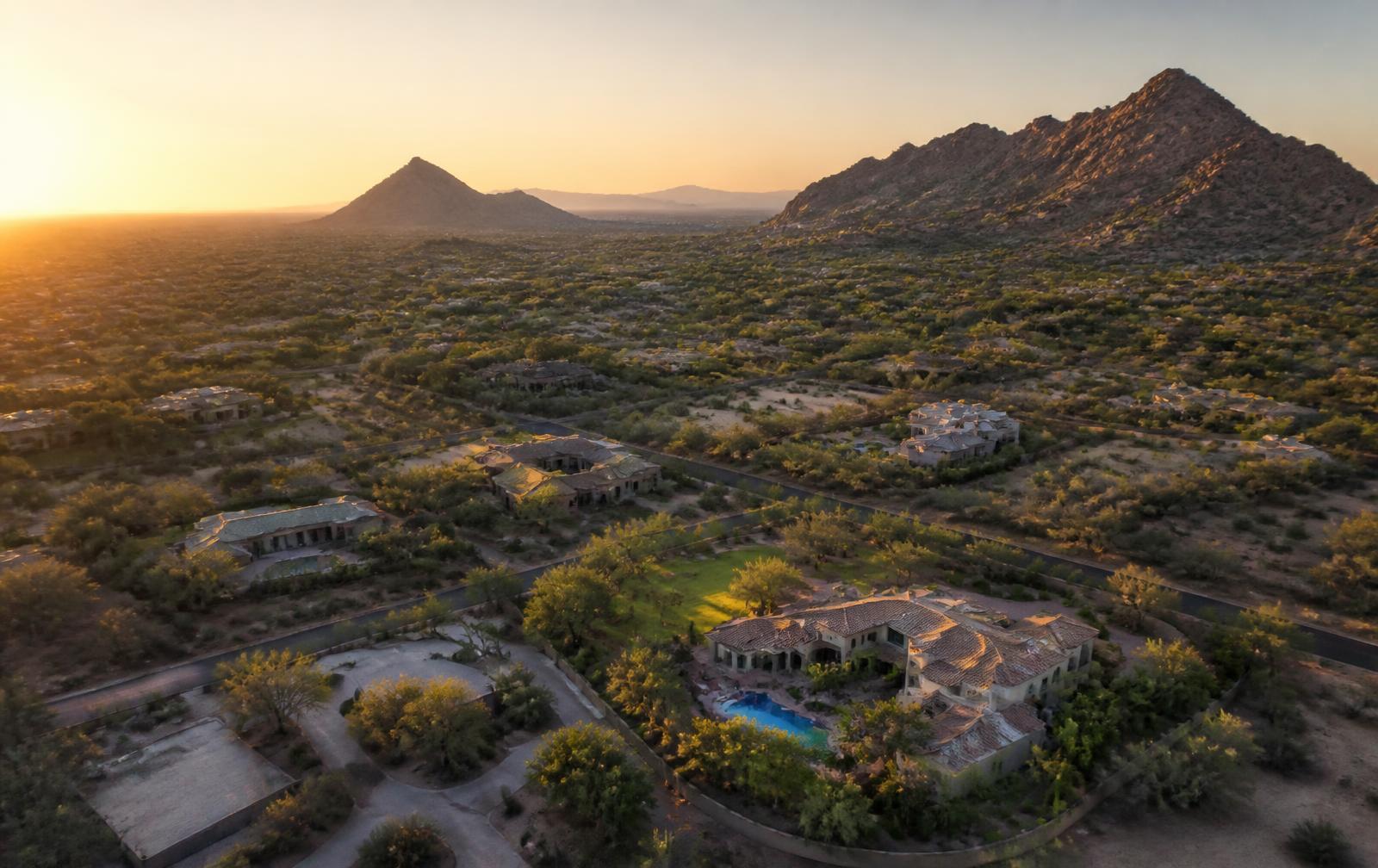 Aerial view at sunrise of a Paradise Valley luxury neighborhood with Camelback and Mummy Mountain silhouettes