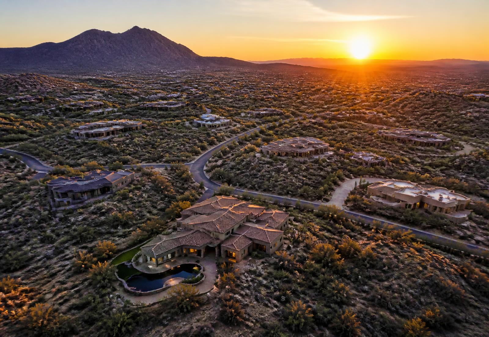 Aerial view at sunset of a large-lot North Scottsdale luxury neighborhood with custom estates set into natural Sonoran Desert terrain